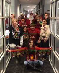 PCI employees pose in Christmas sweaters for a group photo.