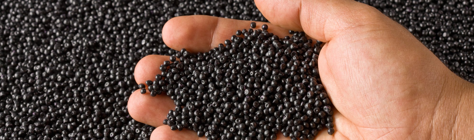 A hand holding polymer resin pellets.